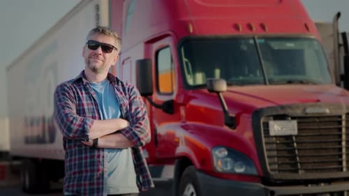 Professional Truck Driver Approaches His Truck and Behind Him Parked Long Haul SemiTruck