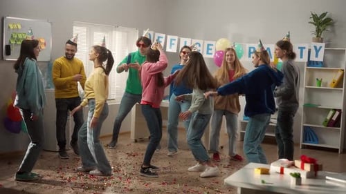 A Group of Colleagues in Festive Hats and Glasses are Dancing Having Fun Celebrating a Common