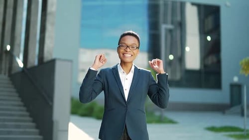happy cheerful african american business woman in suit joyfull walks in urban city street.