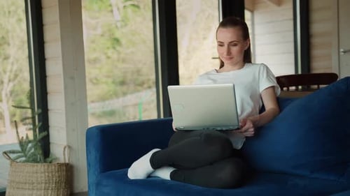 Woman Working on Laptop on Couch Indoors