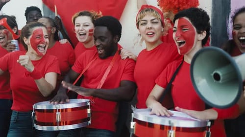 Multiracial football fans exulting while watching soccer game at stadium