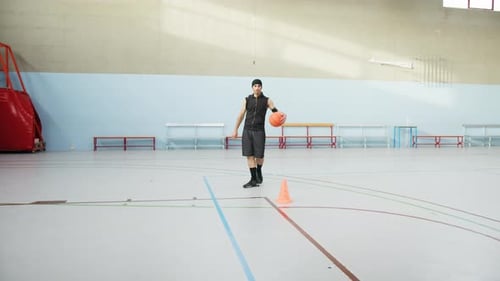 Un joueur de basket dribble autour des quilles avant le match