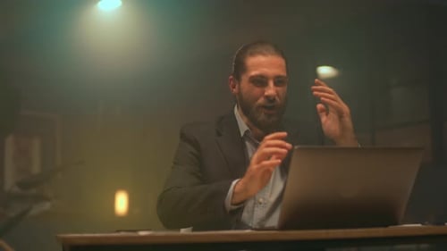 Man Celebrating Success at Desk with Laptop