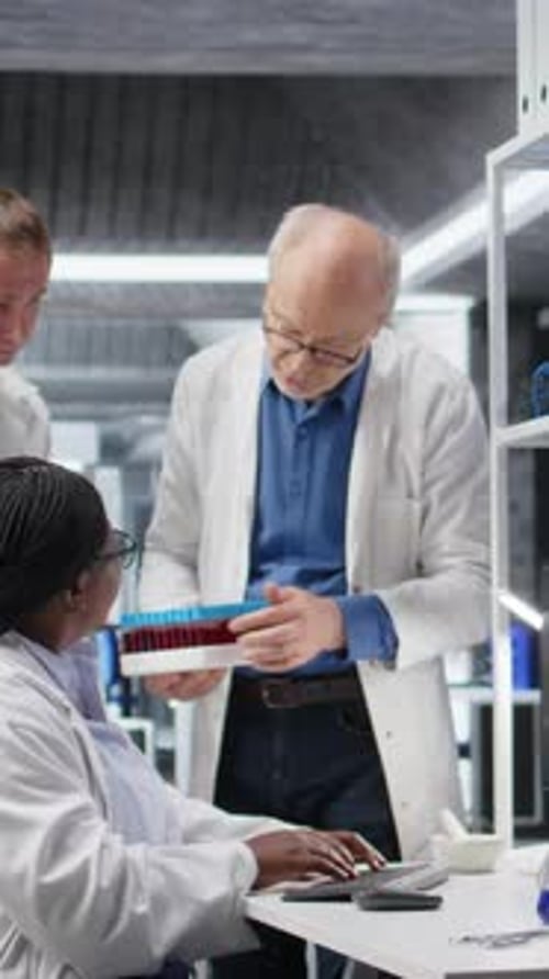 Vertical Video Scientists Team Handles Blood Samples in Test Tube Within Laboratory