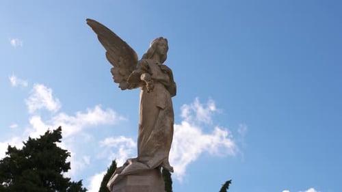 Statue of an angel with clouds timelapse in the background