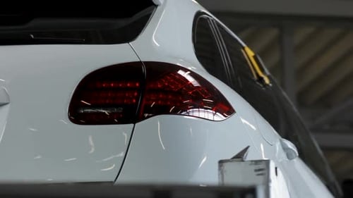 Close-up of a white luxury car's taillight with reflective surfaces