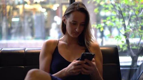 Young Woman Texting, Surfing Web on Smartphone Sitting in Cafe Adult