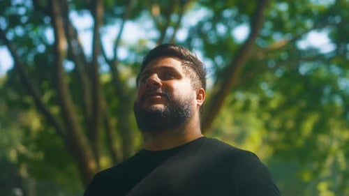 Close up young happy bearded man standing in nature breathes fresh air. Male enjoying a life of peac