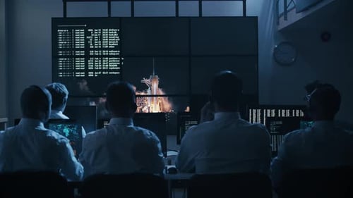 Un grupo de personas en el centro de control de la misión se llenó de pantallas para celebrar el exitoso lanzamiento de un cohete
