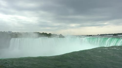 Niagara Falls landscape view of water flowing down the waterfall creating steam, on a cloudy day