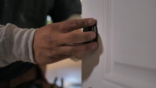 Trabajador instalando una cerradura de puerta, HD