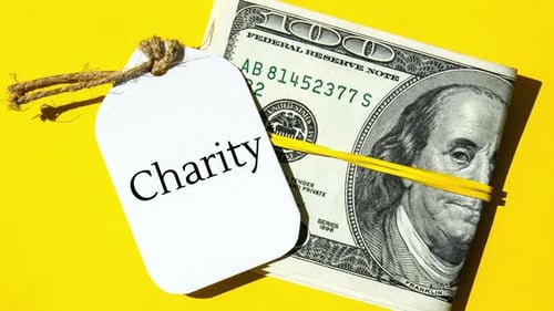 Zoom in Out Paper Note Written Word CHARITY in Black Letters Around Dollar Banknotes