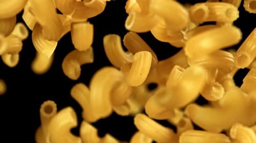 Elbow Macaroni Pasta Falling Against Black Background