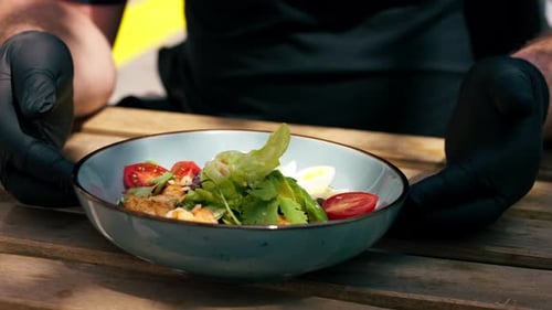 Closeup in Restaurant on the Street on a Wooden Table the Chef Puts on the Table a Blue Plate with a