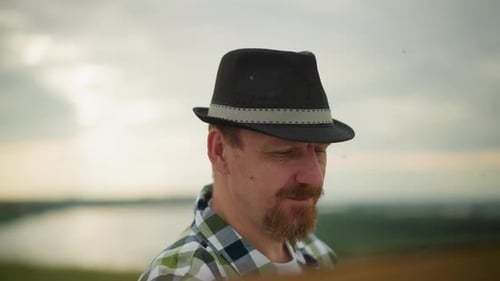 Man Wearing Hat Gazing at River and Landscape