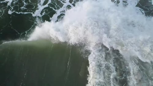 Aerial view of large waves crashing on the beach in the Monterey Bay.