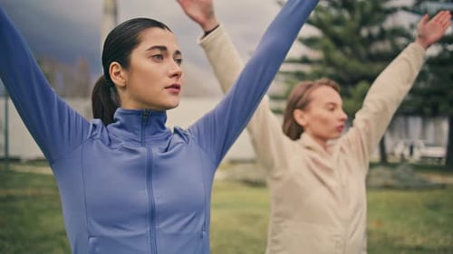 Women Stretching Arms in Park, Performing Wellness Routine