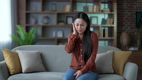 Young Adult Woman with Ear Pain on Couch