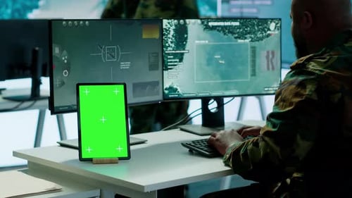 Man in Camouflage Typing with Green Screen Tablet