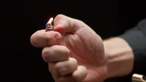 Un homme tient un briquet touristique en feu sur fond noir