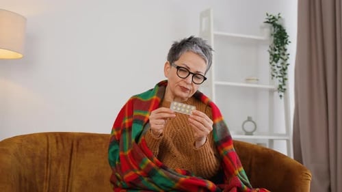 Sick Woman with Pills Covered with Warm Blanket