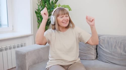 Woman Enjoys Music, Dancing on Sofa Indoors