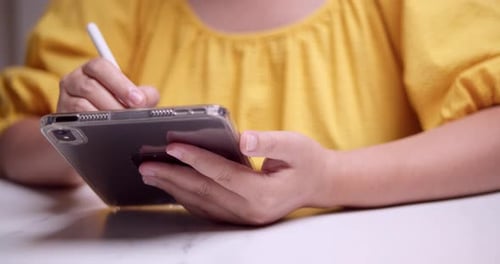 Hands Using Tablet and Stylus at Table Indoors