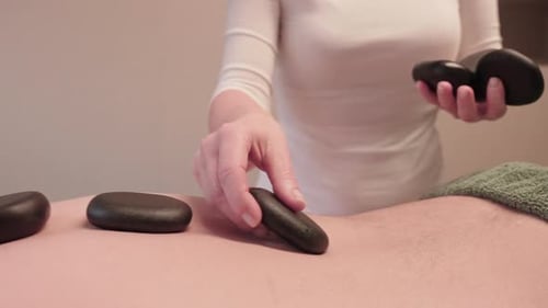 Volcanic Rocks on Back of Man, Lava Stone Massage Treatment in Wellness Spa Center, Close Up