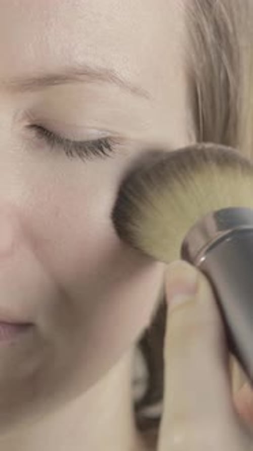 Woman Applying Makeup with a Brush Close Up
