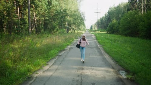 Young Woman Dragging Hoodie Rope While Walking On Quiet Forest Path