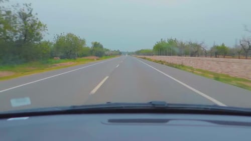 A fast straight drive on a highway from the lush green environment, captured from the car windscreen