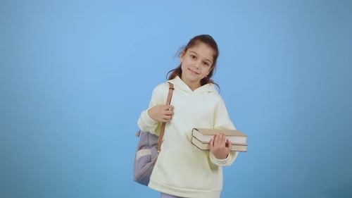 Young Girl Holding Books Gives Thumbs Up