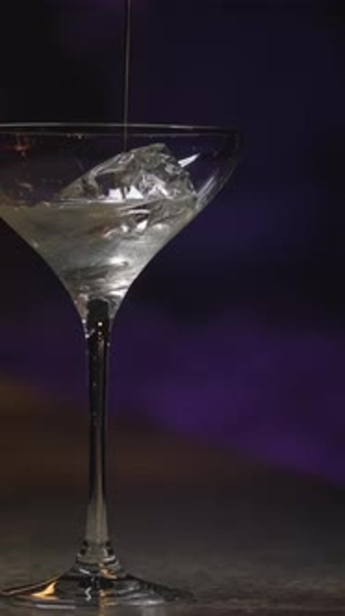 Close Up of Pouring Alcohol Into the Martini Glass with Ice Cube Stock Footage Thick Alcoholic