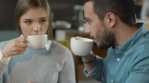 Attractive Young Man and Woman are Sitting Talking at Cozy Coffee Shop.