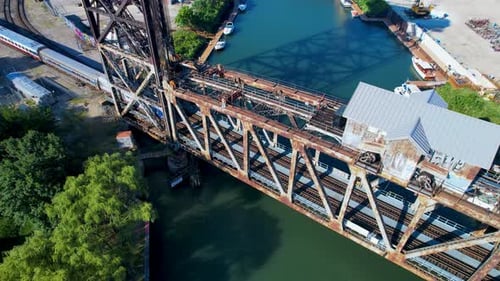 Passenger Train Crosses Over River On Old Bridge Above View