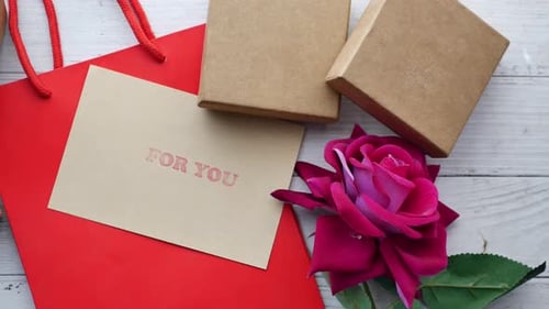 Top View of Gift Box and Rose Flower on Red Background