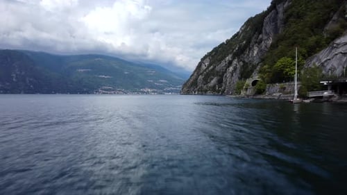 FPV drone flying low and fast over Lake Como water in Alps of Italy