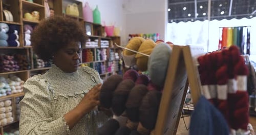 Female Business Owner Restocking Balls Of Yarn On Display In Store Slow Motion
