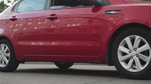 Elegant Red Car Drives on Asphalt Road in Center of City