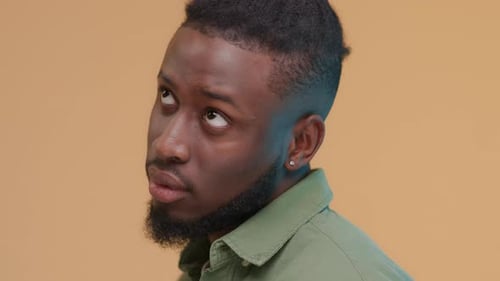 Thoughtful Man with Dreadlocks Looking Upward in Studio