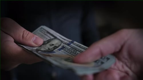 Two people can not share the money pull each other pack of 100 dollar bills, close-up