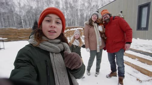 Family Poses for Smartphone Video in Snowy Yard