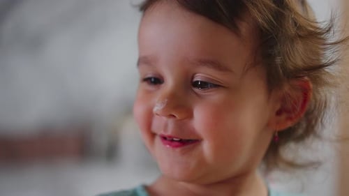 Adorable toddler with brown hair smiling indoors