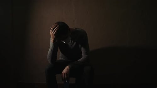 Sad Man Sitting Alone in Dark Room with Mask