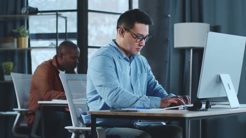 Man Typing on Computer in Modern Office