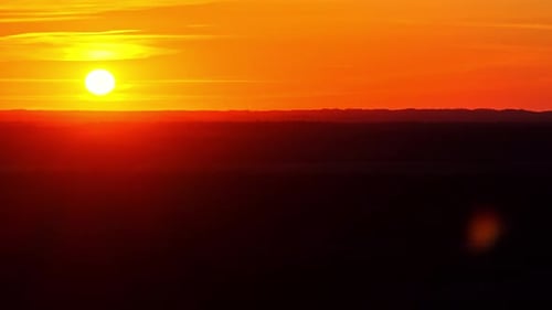 Goldener Sonnenuntergang über einem silhouettierten Horizont mit dramatisch orangefarbenem Himmel