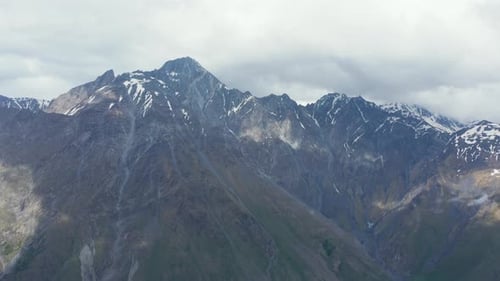 Stunning aerial panoramic view of mountain range. Bright day, sky covered with clouds, casting shado