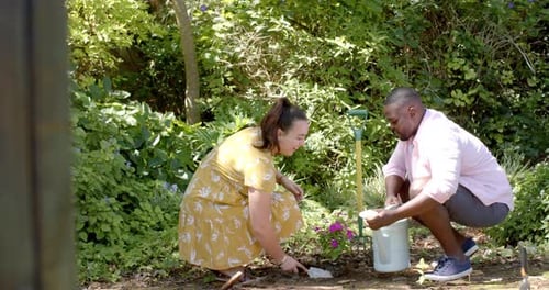 Gardening together, diverse friends planting flowers and watering plants in backyard garden