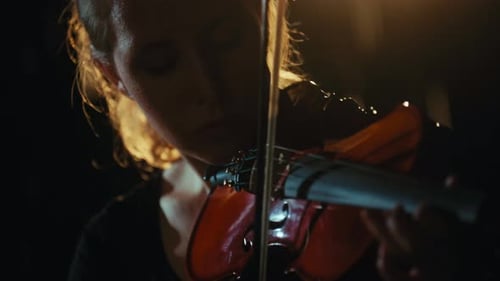Woman Plays Violin in Dramatic Lighting