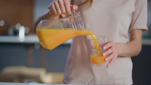 Woman Pours and Enjoys Orange Juice in Kitchen